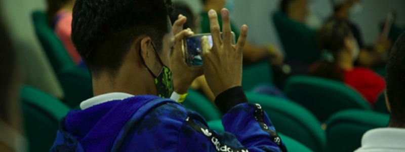 persona con un celular en las manos sentado en un auditorio