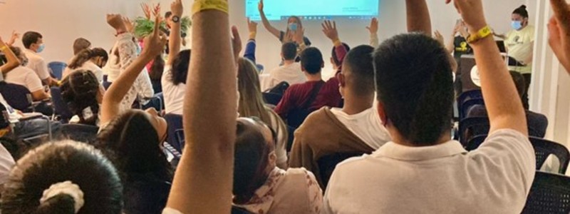 personas sentadas en un auditorio levantando las manos