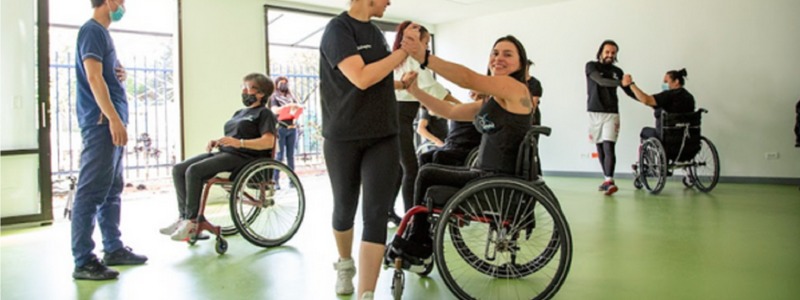 En la foto: Aura Lorena Varela, en silla de ruedas, bailando con una persona caminante.