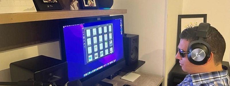 Alejandro frente a su computador utiliza unos audífonos inalámbricos