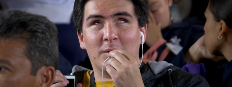En la foto: Persona con discapacidad visual manipula un celular y usa audífonos
