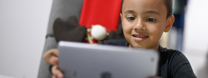 Niño interactúa con una tablet que tiene en sus manos