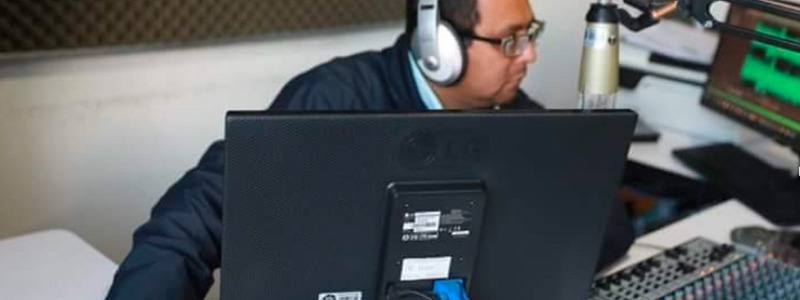 Un señor con unos audifonos y trabajando con el computador